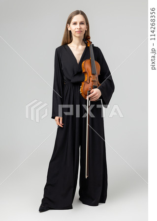 Attractive woman wearing elegant outfit playing violin 114268356