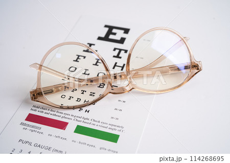Glasses on eye testing exam chart to check eyesight accuracy of reading. Glasses on eye testing exam chart to check eyesight accuracy of reading. 114268695