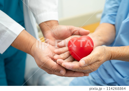 Doctor give red heart to Asian elderly woman patient in her hand on bed in hospital. 114268864