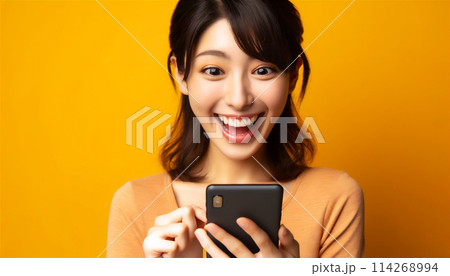 スマホを見て驚き喜ぶ女性 114268994