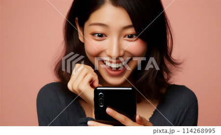 スマホを見て驚き喜ぶ女性 114268995