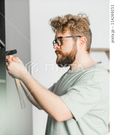 Portrait of man assembling furniture. Do it yourself furniture assembly at home Portrait of man assembling furniture. Do it yourself furniture assembly at home 114269251