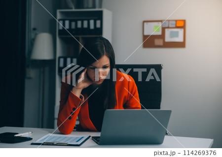 Portrait of tired young business Asian woman work with documents tax laptop computer in office. Sad, unhappy, Worried, Depression, or employee life stress concept Portrait of tired young business Asian woman work with documents tax laptop computer in office. Sad, unhappy, Worried, Depression, or employee life stress concept 114269376