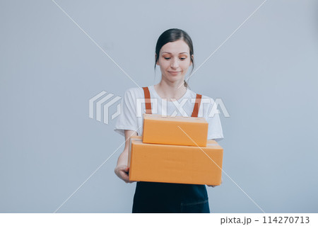 Smiling Asian woman in casual clothes holding a cardboard box mockup while standing against an isolated white background. shipping business concept 114270713
