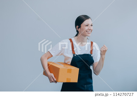 Smiling Asian woman in casual clothes holding a cardboard box mockup while standing against an isolated white background. shipping business concept Smiling Asian woman in casual clothes holding a cardboard box mockup while standing against an isolated white background. shipping business concept 114270727