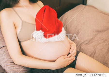 Pregnant in santa hat holding her belly. Christmas and New year concept Pregnant in santa hat holding her belly. Christmas and New year concept 114270938