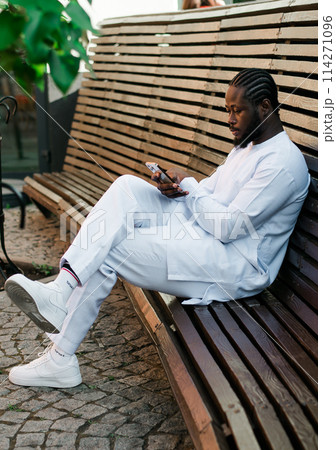Millennial generation african american man typing sms outdoor 5g internet concept. High speed internet on phone and chatting on social networks and blog concept 114271096