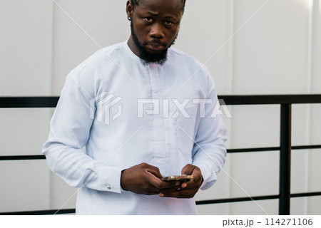 Millennial generation african american man typing sms outdoor 5g internet concept. High speed internet on phone and chatting on social networks and blog concept 114271106