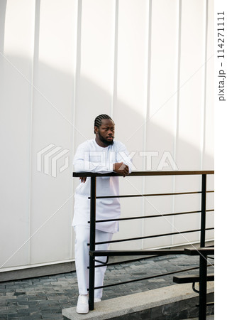 Cheerful male tourist dress in white wear dashiki ethnic smiling at city street on stairs. African American travel model have free time. Copy space 114271111