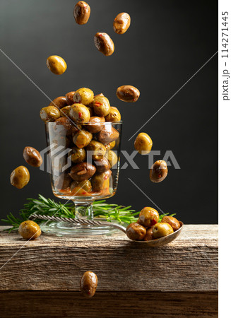 Spicy olives and rosemary twigs on a wooden table. 114271445