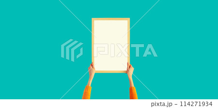 Woman decorating interior, hanging white blank photo frame, wooden picture on wall in new house 114271934