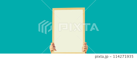 Woman decorating interior, hanging white blank photo frame, wooden picture on wall in new house 114271935