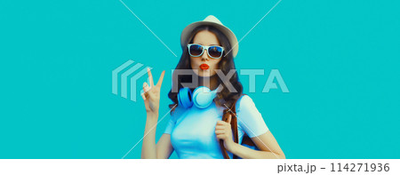 Happy modern happy young woman listening to music with headphones on blue background 114271936