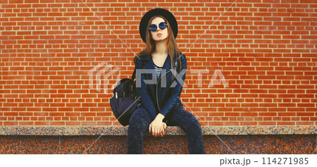 stylish young woman model wearing black round hat, leather jacket in rock style on city street stylish young woman model wearing black round hat, leather jacket in rock style on city street 114271985