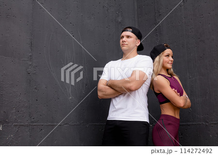 Smiling sportive caucasian couple posing over grey background Smiling sportive caucasian couple posing over grey background 114272492