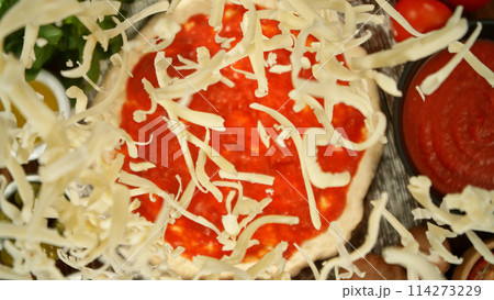 Super slow motion of falling various ingredients on pizza dough with sugo, top down view Super slow motion of falling various ingredients on pizza dough with sugo, top down view 114273229