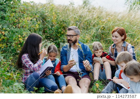 Young students learning about nature, forest ecosystem during biology field teaching class, observing wild plants. Dedicated teachers during outdoor active education. Young students learning about nature, forest ecosystem during biology field teaching class, observing wild plants. Dedicated teachers during outdoor active education. 114273587