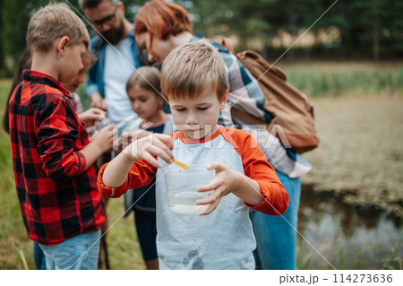 Young students analyzing water quality, ph level with indicator strips during biology field teaching class. Female teacher during outdoor active education. 114273636