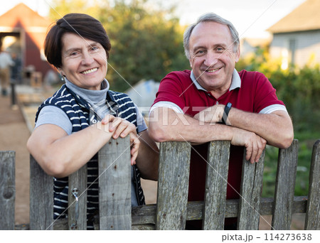 Portrait of a happy elderly couple in the garden near fence of their farm 114273638