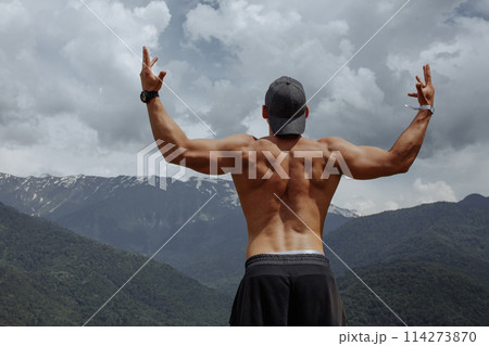 Bodybuilder posing in mountains. Handsome strong man showing his muscles. 114273870