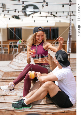Sportive couple sitting in a cafe enjoying fresh drinks after intensive workout. Sportive couple sitting in a cafe enjoying fresh drinks after intensive workout. 114273907