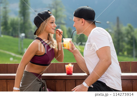 Sportive couple sitting in a cafe enjoying fresh drinks after intensive workout. Sportive couple sitting in a cafe enjoying fresh drinks after intensive workout. 114273914