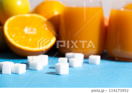 Sugar content in fruit juices. Sugar cubes and glasses of multifruit juice. Sugar content in fruit juices. Sugar cubes and glasses of multifruit juice. 114273952