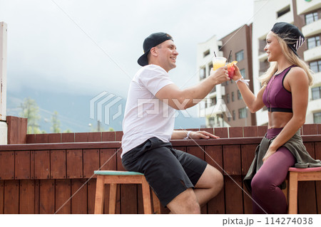 Sportive couple sitting in a cafe enjoying fresh drinks after intensive workout. Sportive couple sitting in a cafe enjoying fresh drinks after intensive workout. 114274038