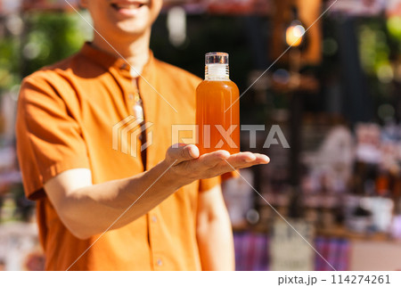 Happy man hand holding a bottle of orange juice Happy man hand holding a bottle of orange juice 114274261
