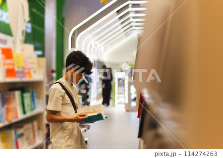 Young boy reading book in a book store. Young boy reading book in a book store. 114274263