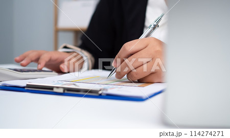 Photo close up hands of business woman working on desk office with using a calculator to calculate the numbers, Finance accounting concept, Accounting checking company budget accounting documents. 114274271