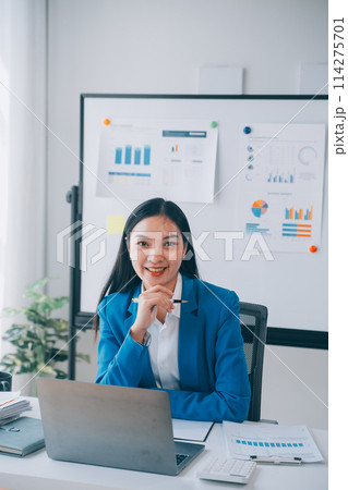 Cheerful business lady working on laptop in office, Asian happy beautiful businesswoman in formal suit work in workplace. Attractive female employee office worker smile. 114275701