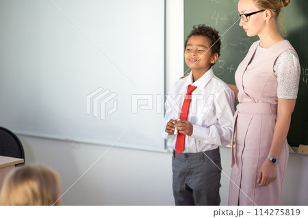 boy solving addition and subtraction on board. schoolboy writing solution of mathematical operation 114275819