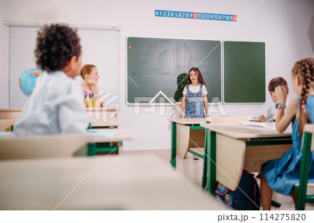 Schoolchild with teacher in classroom. Girl near chalkboard show her homework Schoolchild with teacher in classroom. Girl near chalkboard show her homework 114275820