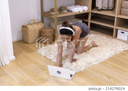 Young Sport Women look at laptop online trainer home fitness workout exercise in living room. Woman using laptop on floor in sportswear arms stretching body weight traning. Healthy lifestyle concept 114276024