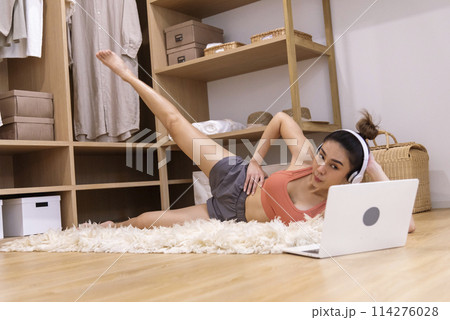 Young Sport Women look at laptop online trainer home fitness workout exercise in living room. Woman using laptop on floor in sportswear arms stretching body weight traning. Healthy lifestyle concept 114276028