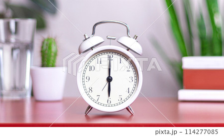 Classic white clock on a table. The clock hand points to 6 114277085