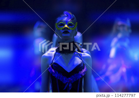 A girl dances in a show or circus in the blue rays of stage lighting. Theatrical performance. A girl dances in a show or circus in the blue rays of stage lighting. Theatrical performance. 114277797