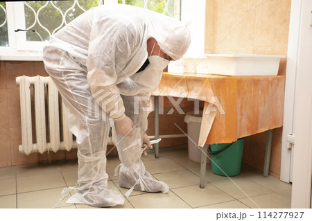 The doctor takes off his protective suit in the hospital during the coronavirus epidemic. 114277927