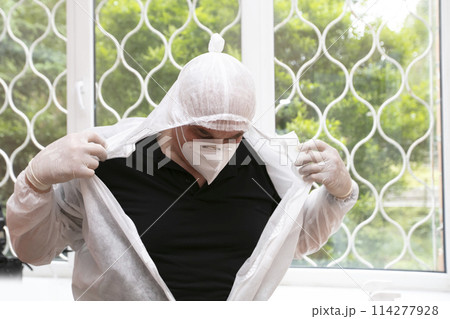 The doctor takes off his protective suit in the hospital during the coronavirus epidemic. 114277928