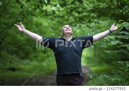 A happy middle-aged man is walking in a beautiful forest. 114277931