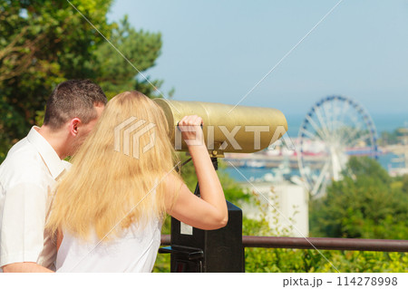 Happy couple looking through city telescope Happy couple looking through city telescope 114278998