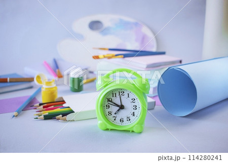 Back to school concept, on the student desk there are stationery, colored pencils, a palette with paints and rolls of paper on a light background, pastel colors 114280241