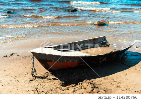An old fishing boat is docked on a sandy beach in a sunny bay 114280766