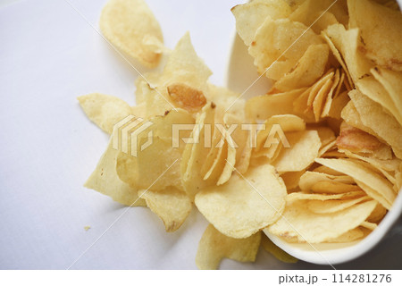 Delicious salted potato chips in a cardboard jar on a white background. Fast food. 114281276