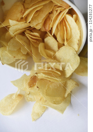 Delicious salted potato chips in a cardboard jar on a white background. Fast food. 114281277