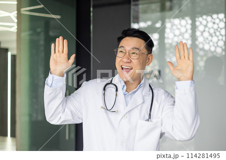 A joyful mature Asian doctor celebrates by dancing in his clinic, wearing a stethoscope and a lab coat, showing happiness and positivity in healthcare. A joyful mature Asian doctor celebrates by dancing in his clinic, wearing a stethoscope and a lab coat, showing happiness and positivity in healthcare. 114281495
