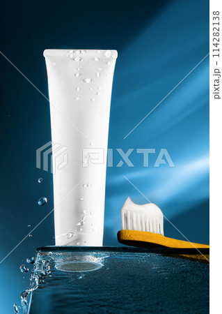 Toothpaste tube with copy space and droplets, bamboo toothbrush on reflective blue surface. Concept oral health and sustainable hygiene products. Mock up.International Dentist Day. National Brush Day. 114282138