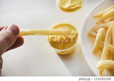 French fries on a white plate with sauce. Delicious fried crispy potatoes. 114282266