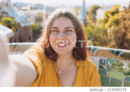 Beautiful female in Gaudi garden, Spain, Barcelona. Young traveling woman taking selfie outdoors. Concept of travel, tourism and vacation in city 114282272